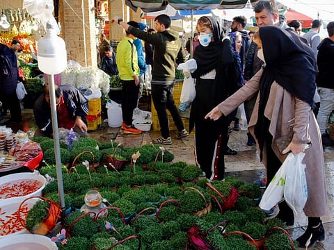 Iranians, some wearing protective face masks as a means of protection against the novel coronavirus, choose green sprouts as part of the seven traditional items set on a table, ahead of Nowruz, the national New Year 2-week celebration, at the Tajrish Bazaar in Tehran on March 19.