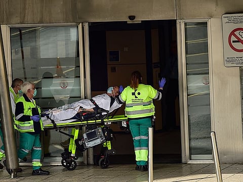 Ambulances medical staff deliver a patient wearing protection masks at Cruces hospital, in Bilbao, northern Spain, Saturday, March 21, 2020.