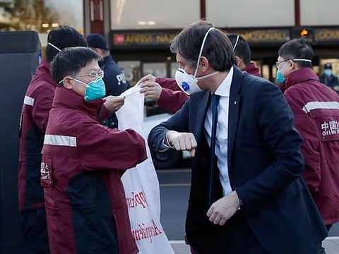 Vice President of Region Lombardy Fabrizio Sala, right, salutes with his forearm medics and paramedics from China upon arrival at the Malpensa airport of Milan, Wednesday, March 18, 2020. Some 37 between doctors and paramedics were sent along with some 20 tons of equipment, and will be deployed to different hospitals in Italy's most affected area. 