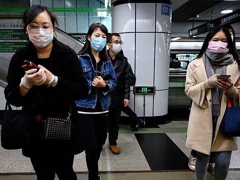 People wearing face masks, amid concerns over the spread of the COVID-19 novel coronavirus, wait for a train at a subway station in Shanghai on March 23, 2020.