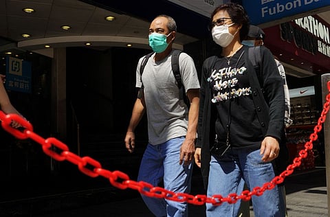 People wearing face masks walk at a down town street in Hong Kong on Monday, March 23, 2020.
