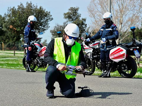 In this Friday, March 20, 2020, photo, police officers with help from a drone monitor citizens' movements demonstrate in Grosseto, central Italy
