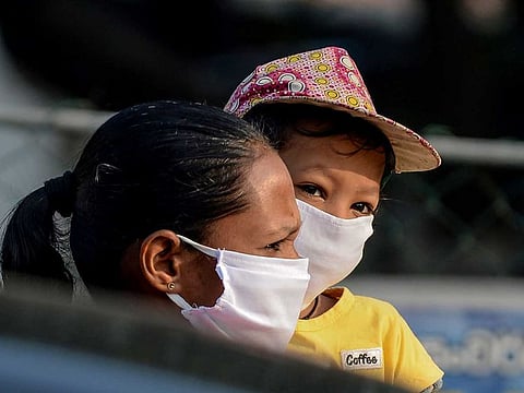 A woman and child wait outside a shop at Piliyandala on the outskirts of Sri Lanka's capital city Colombo on March 24, 2020, as the authorities briefly lifted a curfew to allow residents to stock up on essentials amid concerns over the spread of the COVID-19 virus.