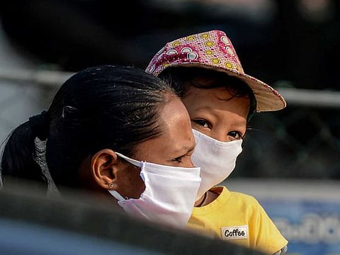 A woman and child wait outside a shop at Piliyandala on the outskirts of Sri Lanka's capital city Colombo on March 24, 2020, as the authorities briefly lifted a curfew to allow residents to stock up on essentials amid concerns over the spread of the COVID-19 virus.