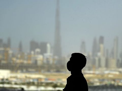 File image: A man wearing a protective mask stands at a racetrack overlooking Dubai 