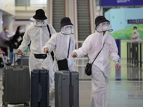 Passengers wear protective suits and face masks as they arrive at the Hong Kong airport, on Monday, March 23, 2020.
