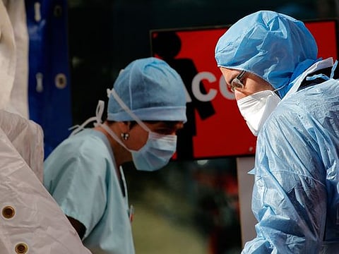 Doctors speak outside a tent used as a waiting room for people with covid-19 symptoms set up at the Tenon hospital in Paris.