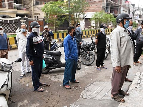 People wait for their turn to buy medicine outside a pharmacy during a government-imposed nationwide lockdown as a preventive measure against the COVID-19 coronavirus in Amritsar on March 28,2020