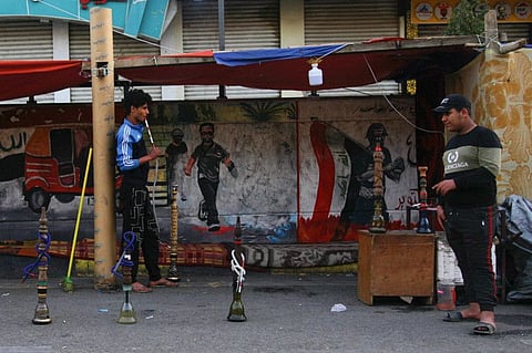 In this March 19 photo,  a man smokes waterpipe at Tahrir square, Baghdad. As the coronavirus spreads across the Middle East, cherished traditions are coming to an abrupt halt: no more coffee shops where men gather to play cards and backgammon. And most importantly, no more smoking of the beloved shisha, or waterpipe, in public places.