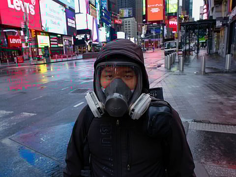 A man wears a face mask while he visits Times Square as rain falls on March 28 in New York City. US President Donald Trump said on March 28, 2020 that he's considering a short-term quarantine of New York state, New Jersey, and parts of Connecticut. 