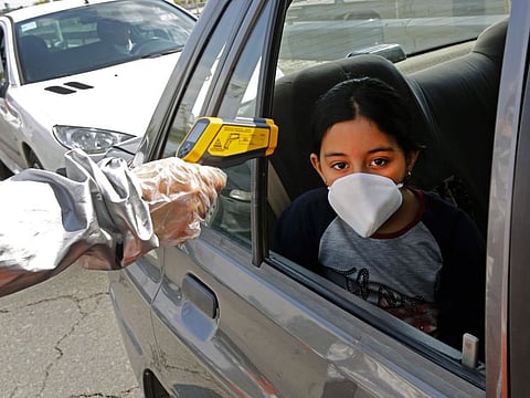 A file photo taken on March 26 shows a member of the Iranian Red Crescent testing people for coronavirus symptoms, as police blocked Tehran to Alborz highway to check every car following orders by the Iranian government.