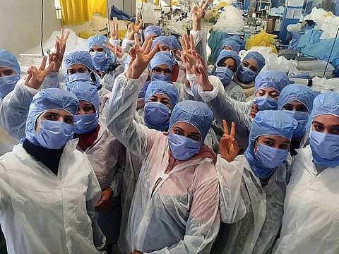 Tunisian women cheering as they work on the production of medical masks in the company's factory in the central city of Kairouan.