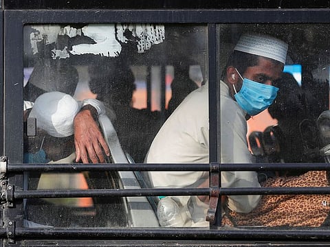 Men wearing protective masks sit inside a bus that will take them to a quarantine facility, amid concerns about the spread of coronavirus disease (COVID-19), in Nizamuddin area of New Delhi, India, March 31, 2020. 