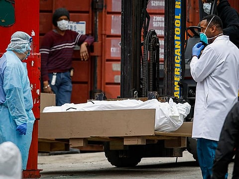 A body wrapped in plastic is prepared to be loaded onto a refrigerated container truck used as a temporary morgue by medical workers due to COVID-19 concerns, Tuesday, March 31, 2020, at Brooklyn Hospital Center in the Brooklyn borough of New York. The new coronavirus causes mild or moderate symptoms for most people, but for some, especially older adults and people with existing health problems, it can cause more severe illness or deat