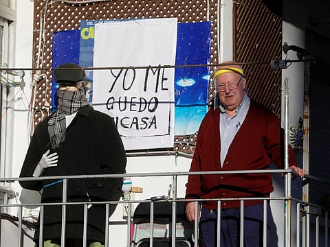 Jose Maria Leon, 77, wears a protective face shield as he stands on the balcony of his flat, next to a dressed mannequin and a sign that reads "I stay at home", during the coronavirus disease outbreak, in Ronda, southern Spain, April 3.