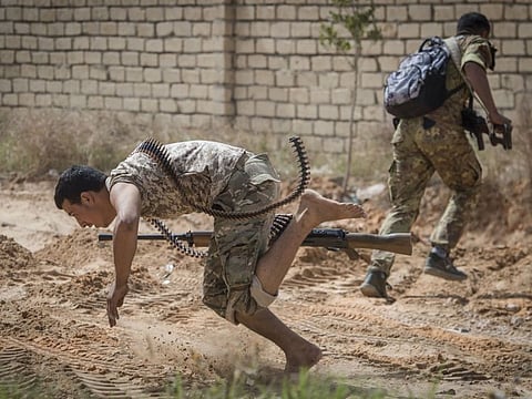 In this file photo taken on April 25, 2019, fighters loyal to the Government of National Accord run for cover during clashes with forces loyal to Gen. Khalifa Haftar south of Tripoli. Despite the COVID-19 outbreak, the conflict in Libya has escalated. 