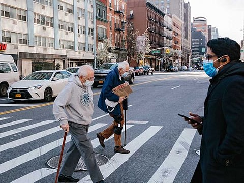 Pedestrians wearing face masks cross the street near Union Square in New York on March 27, 2020. White House advisers and public health officials are engaged in a fierce debate over recommending that all Americans wear masks when they leave their homes, with such a dramatic change in Americans' social behavior deeply dividing the Trump administration. 
