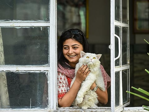 Sana Masroor with her pet cat looks out through a window of her house during the nationwide lockdown, in the old quarters of Delhi on April 4.
