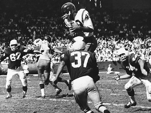 Bobby Mitchell of the Washington Redskins jumps to haul in a pass from quarterback Norman Snead during an NFL game against the St. Louis Cardinals in 1962