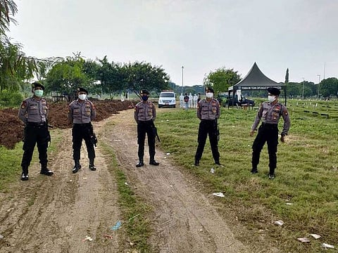 Policemen wear face masks at a cemetery in Jakarta, as they guard workers and family members during funerals for victims of the COVID-19 coronavirus on April 5, 2020. Indonesia's capital Jakarta has launched a special police unit to guard the burials of coronavirus victims over concerns that scared residents could try to block funerals, authorities said on April 5.