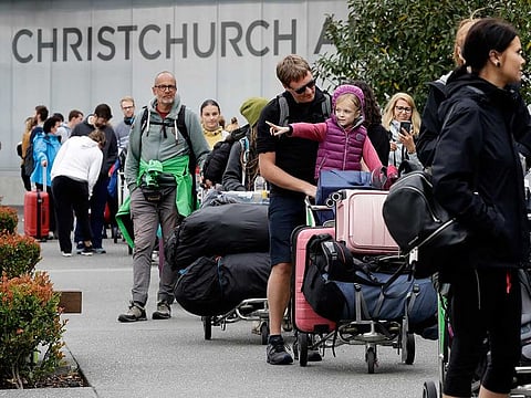 Foreign tourists line up outside the Christchurch Airport terminal as they prepare to check in for a charter flight back to Germany via Vancouver from Christchurch, New Zealand, Monday, April 6, 2020.