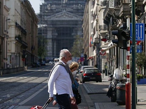 Pedestirans cross an empty street in Brussels, on April 9, 2020, during a lockdown in Belgium to curb the spread of the COVID-19 pandemic, caused by the novel coronavirus.