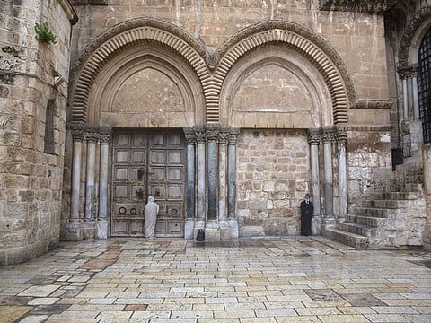 A Christian worshiper stands at the closed door of the Church of the Holy Sepulchre, believed by many Christians to be the site of the crucifixion and burial of Jesus Christ, in Jerusalem, Friday, April 10, 2020.Christians are commemorating Jesus' crucifixion without the solemn church services or emotional processions of past years, marking Good Friday in a world locked down by the coronavirus pandemic.(AP Photo/Sebastian Scheiner)