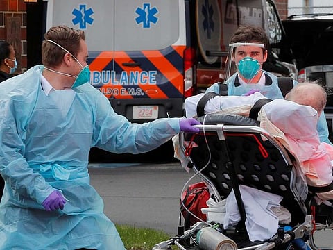 Cataldo Ambulance medics bring a patient who has tested positive for the coronavirus disease (COVID-19) to the ambulance at an assisted living facility in Chelsea, Massachusetts, US, on April 10, 2020.