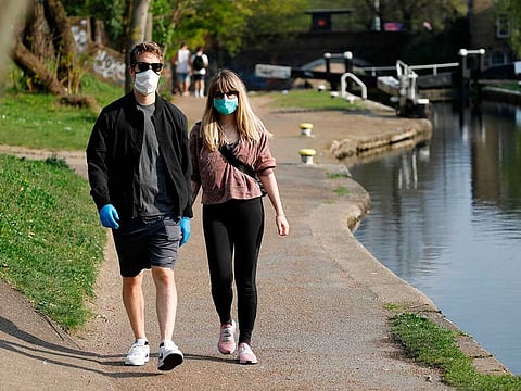 People walk on the towpath by Regent's Canal in east London on April 11, 2020, as life in Britain continues over the Easter break, during the nationwide lockdown to combat the novel coronavirus pandemic.
