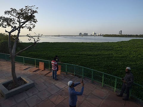 People stand near the banks of the Yamuna river during a government-imposed nationwide lockdown as a preventive measure against the COVID-19 coronavirus, in New Delhi on April 6, 2020. / AFP / Money SHARMA