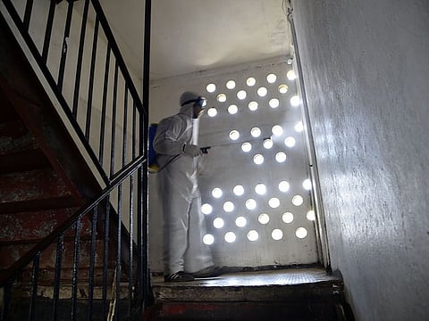 Municipal workers dressed in protective gear disinfect a building during the COVID-19 coronavirus pandemic in the Bab el-Oued district of Algeria's capital Algiers on April 9, 2020.