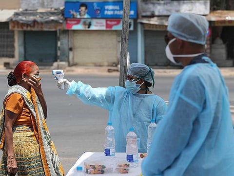 An Indian health worker checks the temperature of a woman during lockdown to prevent the spread of new coronavirus in Ahmedabad, India on April 8, 2020.