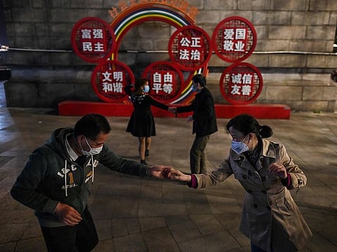 Couples wearing facemasks dance in a park next to the Yangtze River in Wuhan, in China's central Hubei province on April 13, 2020.