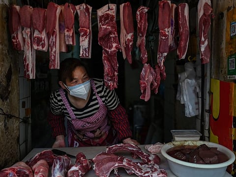 A vendor wearing a face mask waits for customers at her meat stall in Wuhan, China's central Hubei province on April 14. Wuhan was the epicentre of the outbreak. 