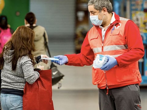 A Spanish public health worker hands out masks on a Madrid street on Monday as Spain eased its coronavirus restrictions, allowing construction workers and others in non-essential industries to return to work for the first time in six weeks. 