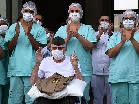 Brazilian 99-year-old former WWII combatant Ermando Armelino Piveta, gestures as leaves the Armed Forces Hospital in Brasilia, after being treated for the novel coronavirus COVID-19 and discharged, on April 14, 2020. Piveta was admitted to hospital on April 6 and treated at the hospital's “COVID Ward”, reserved for positive cases of the disease. 