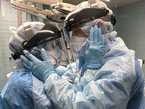 Nurses Mindy Brock and Ben Cayer, wearing protective equipment, hold each other and look into each other's eyes, in Tampa General Hospital in Tampa, Florida