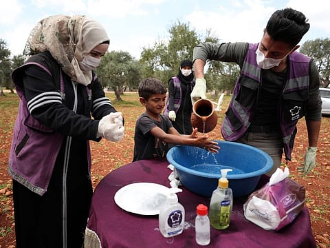 Volunteers from the Violet organisation teach a child how to wash his hands properly at a camp for displaced Syrians, during a campaign to inform children about the novel coronavirus and the methods used in order to limit its spread, in the village of Kafr Yahmul, north of the northwestern Syrian city of Idlib. 