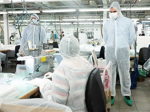 Spanish Prime Minister Pedro Sanchez wearing a full protective suit and a mask looks at people working during a visit at El Corte Ingles retail store sewing workshop amid the coronavirus disease (COVID-19) outbreak in Madrid, Spain, April 15, 2020.