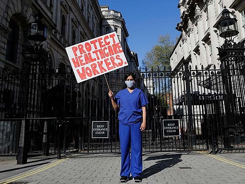 Doctor Meenal Viz holds a banner as she protests outside Downing Street in London, as the country is in lockdown to help curb the spread of the coronavirus, on April 19, 2020. The doctor who is pregnant protested about the lack of PPE and protection for NHS health workers. 