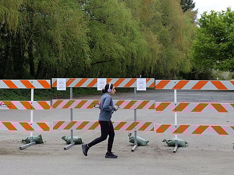 A woman jogs past a barricade outside a park in Salem, Ore. Oregon is in its fourth week of lockdown.