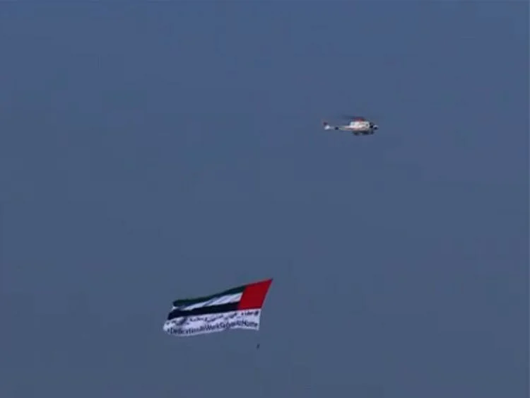 UAE flag with the message #DedicationatWorkandSafetyatHome flown over Abu Dhabi