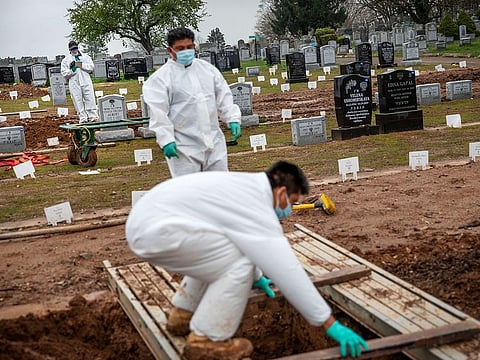 Rabbi Shmuel Plafker, rear, finishes a prayer during the burial service for David Tokar as gravediggers prepare a plot for the next burial at Mount Richmond Cemetery in the Staten Island borough of New York, Wednesday April 8, 2020