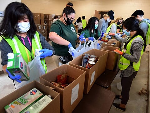 COVID-19: Volunteers in masks and gloves pack groceries at a food bank 