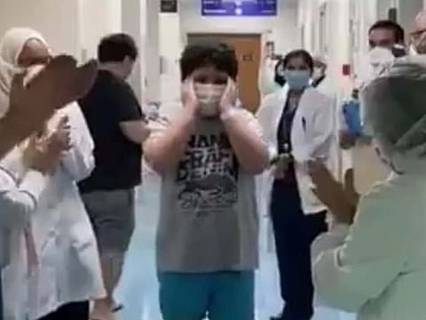 Hervie Emmanuel Magos, 9, is cheered by staff as he leaves the ICU.