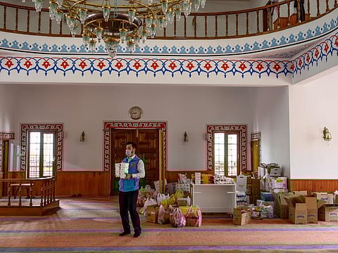 Abdul Samet Cakir, 33, imam of the Dedeman mosque carries goods at the entrance of the Dedeman mosque on April 21, 2020, in the Sariyer district of Istanbul, where the racks reserved for shoes of the Muslim faithful is instead loaded with food which reminds one of a supermarket but they are destined for the needy hard hit by the coronavirus pandemic, after Turkey suspended mass prayers in mosques until the risk of COVID-19 outbreak passes.  / AFP / Bulent Kilic