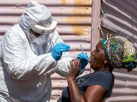 A woman opens her mouth for the health worker to collect a sample for coronavirus testing during the screening and testing campaign aimed to combat the spread of COVID-19 at Lenasia South, south Johannesburg, South Africa