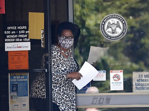 A masked worker at this state WIN job center in Pearl, Miss., holds an unemployment benefit application form as she waits for a client, Tuesday, April 21, 2020. The job centers lobbies are closed statewide to prevent the spread of COVID-19. However the continuing growth of unemployment demands and now additional assistance for self-employed, church employees, gig workers, and others who were previously ineligible for unemployment assistance has drawn some people to the centers for information and to obtain and submit unemployment benefit applications. 