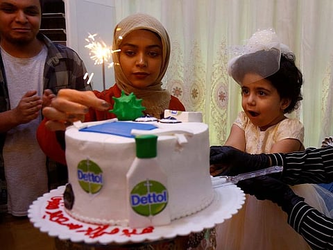 An Iraqi family celebrates their daughter's birthday with a cake with figures of Dettol bottles and models of the coronavirus, during the outbreak of the coronavirus disease (COVID-19), at a cake shop in the holy city of Najaf, Iraq April 24, 2020.