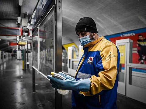 A cleaner wearing a protective face mask and gloves checks what remains of his disinfectant as he is cleaning a coach in a metro station in Vincennes on the outskirts of the French capital Paris, on April 30, 2020, on the 45th day of a lockdown in France aimed at curbing the spread of the COVID-19 disease, caused by the novel coronavirus. French Prime Minister announced on April 28 that face masks will be compulsory on public transport as France will begin a gradual but "risky" return to normality on May 11. 
